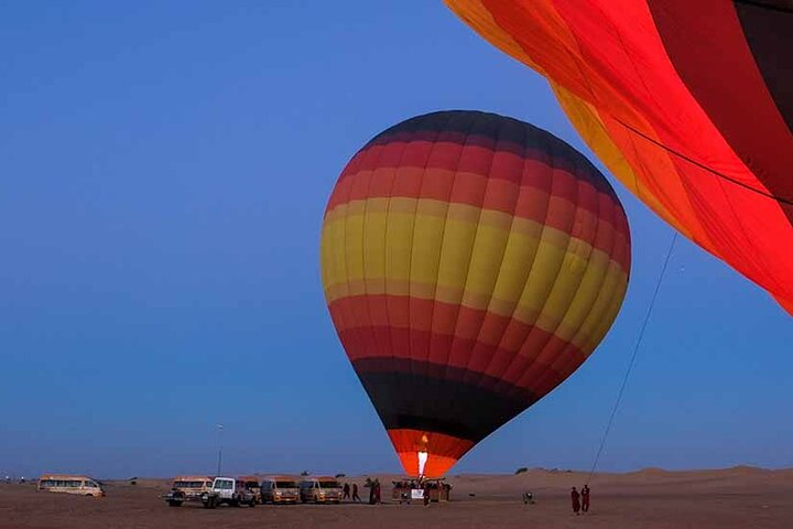 Experience the serene beauty of Dubai's desert as the sun rises revealing stunning landscapes beneath a colorful hot air balloon creating unforgettable memories for every traveler.